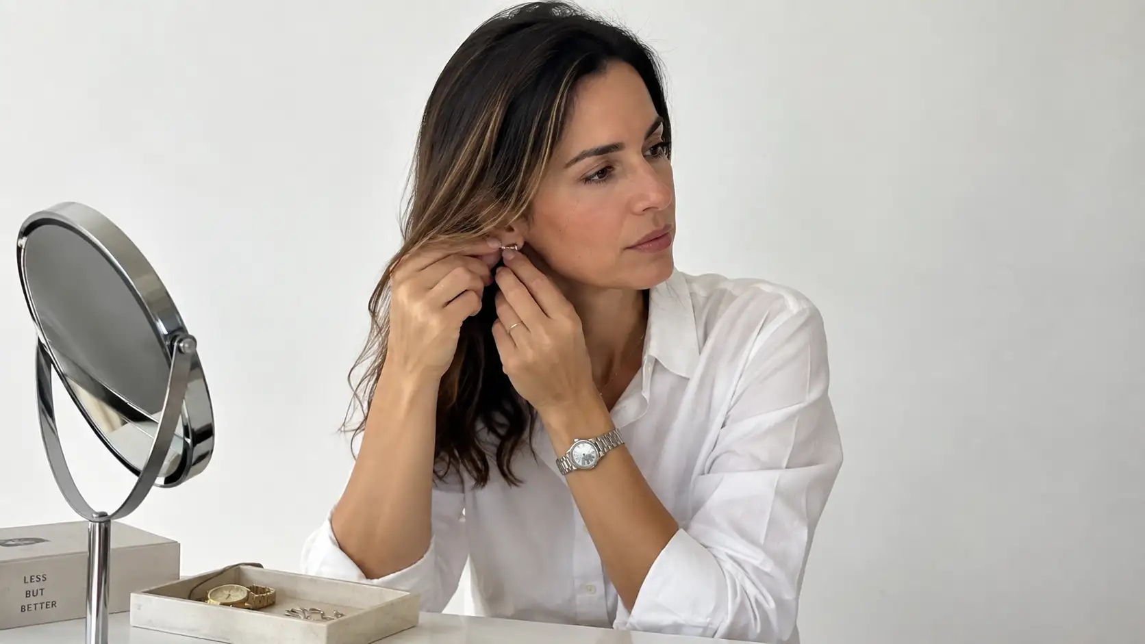 Mulher escolhendo acessórios minimalistas em ambiente clean e sofisticado
